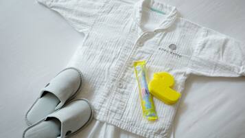 A white shirt with a logo, a pair of white slippers, and a yellow toy.