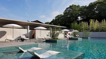 Relax by the pool surrounded by lush greenery and comfortable lounge chairs.