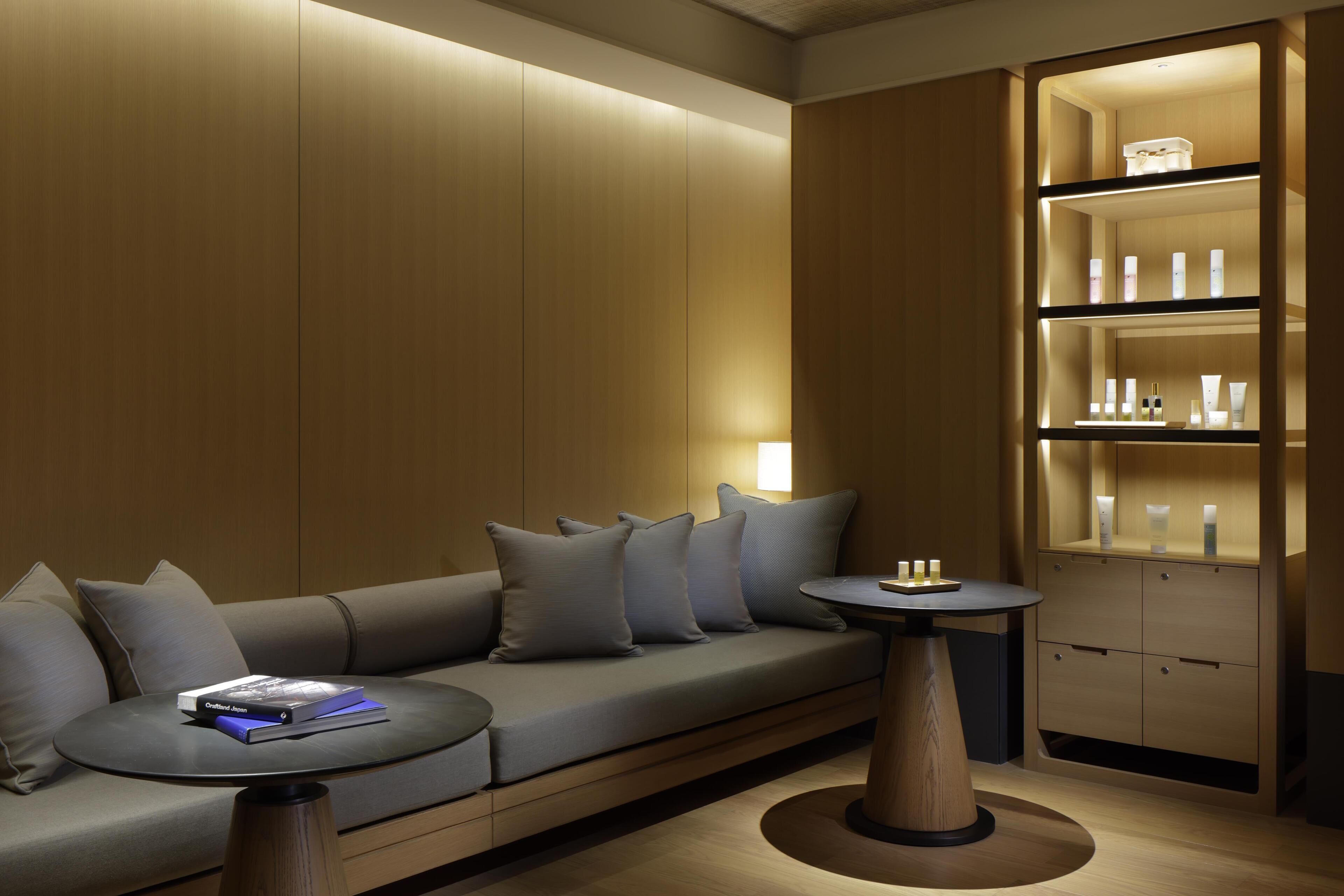 A modern room with a sofa, a small table, and a shelf with toiletries.