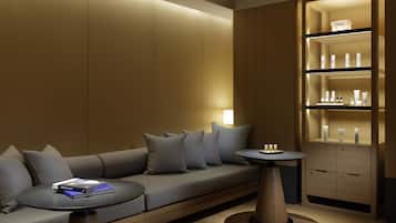 A modern room with a sofa, a small table, and a shelf with toiletries.