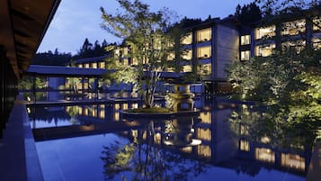 A modern hotel with a reflective pool, surrounded by trees and buildings.