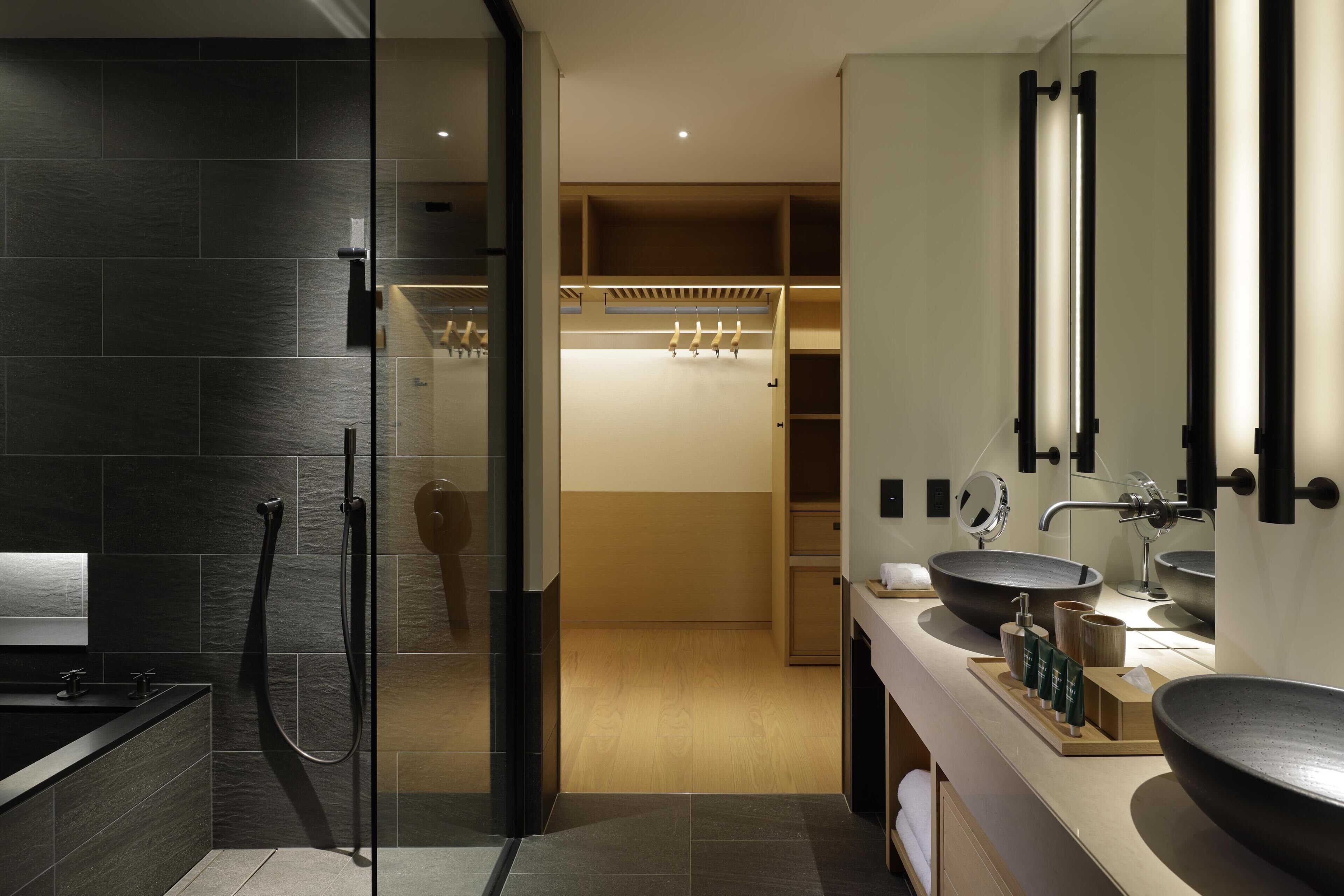 A modern bathroom with a glass-enclosed shower, a large sink, and a walk-in closet.