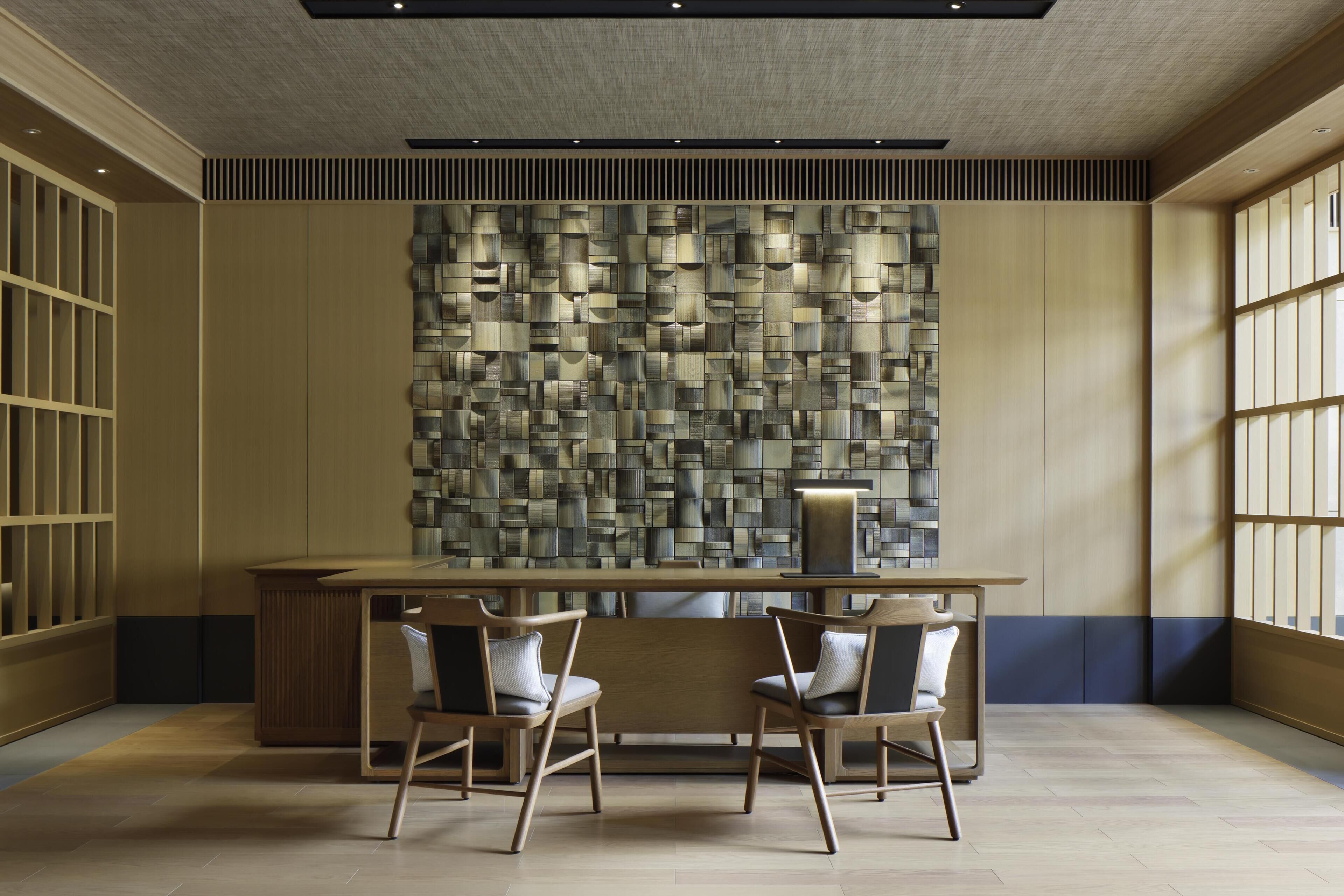 Un interior moderno con una mesa de madera, dos sillas y una pared con textura.
