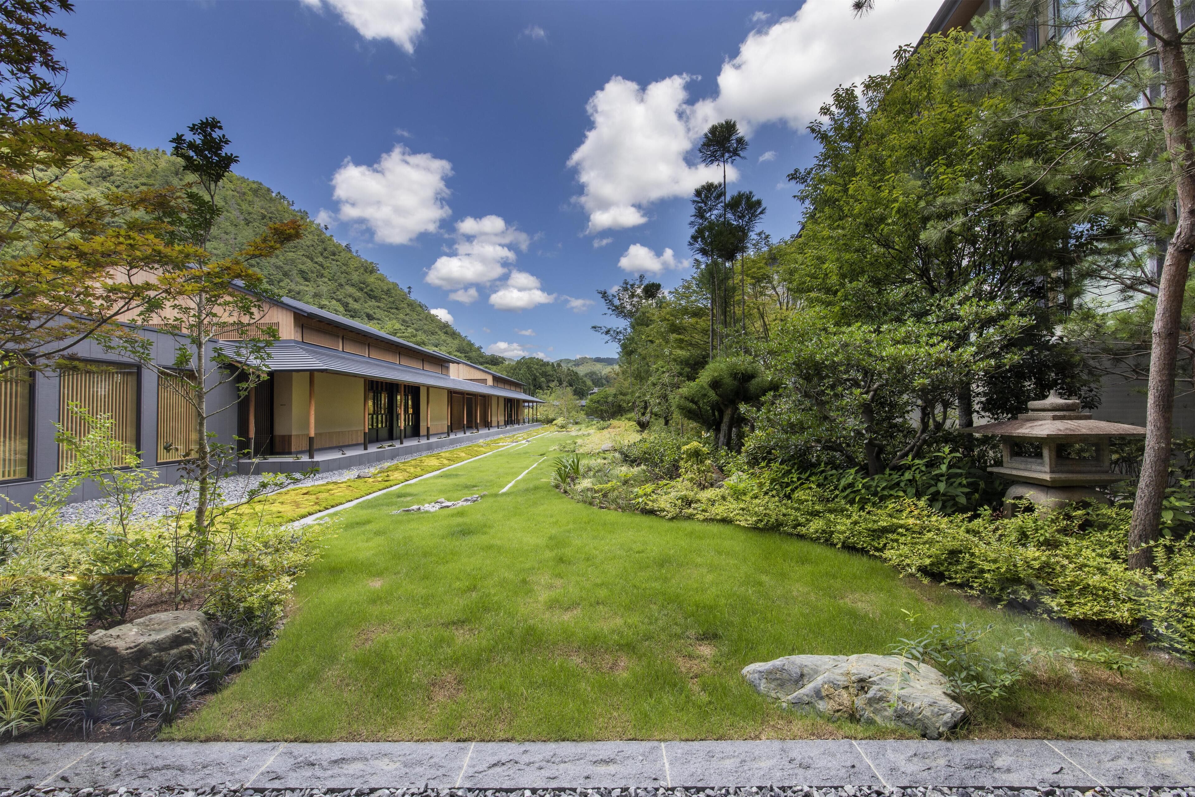 A modern building with a long corridor, a well-maintained garden, and a stone pathway.