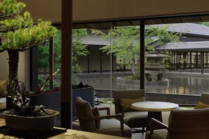 A modern interior with a large window, a bonsai tree, and a seating area with chairs and a table. - ROKU KYOTO, LXR Hotels & Resorts (Kyoto)