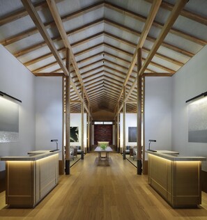 A hotel lobby with a high ceiling, wooden beams, and two reception desks.