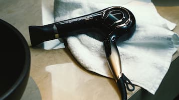 A hair dryer with a cord, placed on a white towel on a countertop.