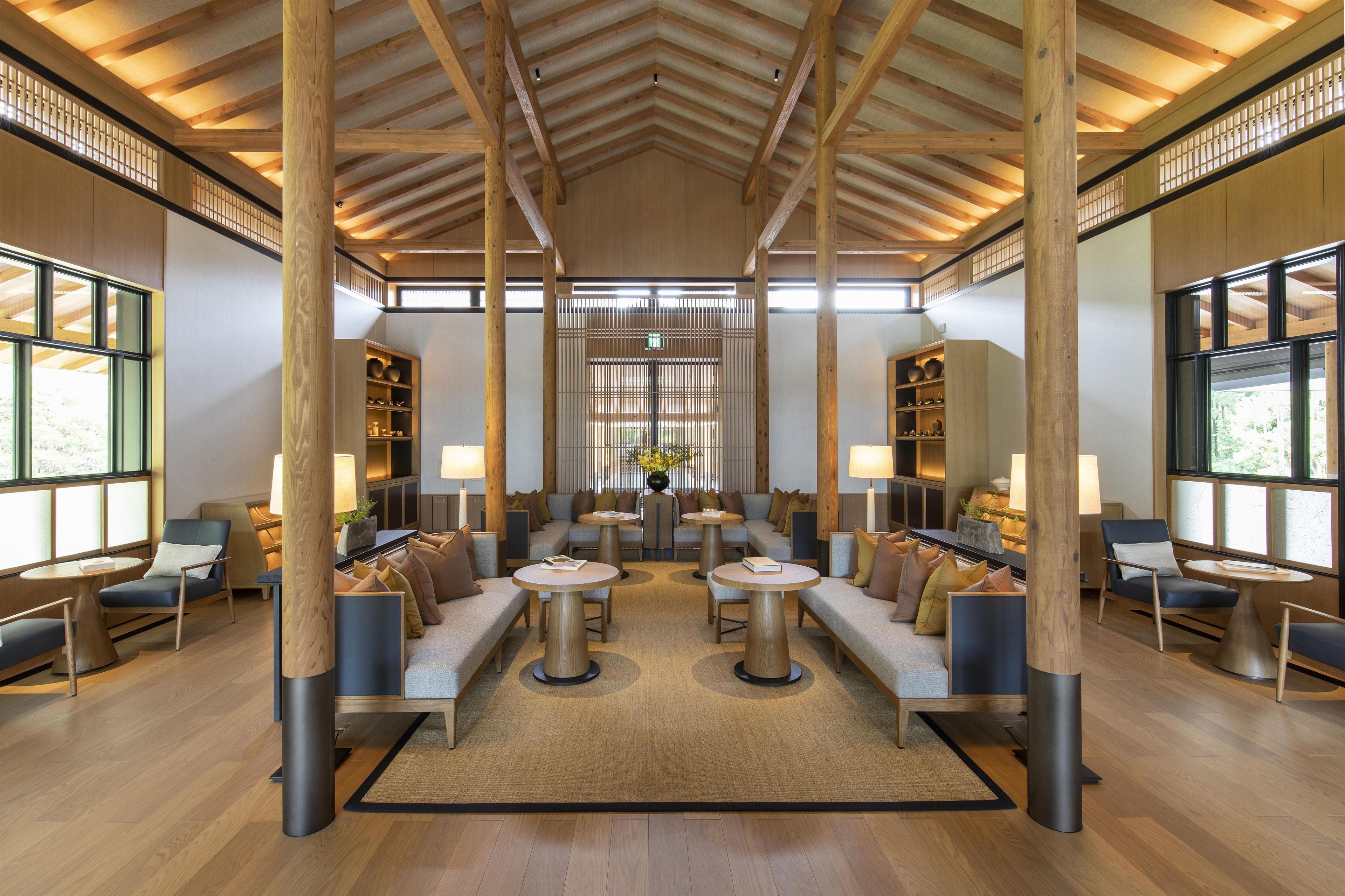 Un hall espacioso con techos altos, vigas de madera y grandes ventanales.