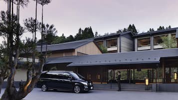 A modern building with a sloped roof, large windows, and a black car parked in front.