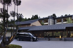 A modern building with a sloped roof, large windows, and a black car parked in front.