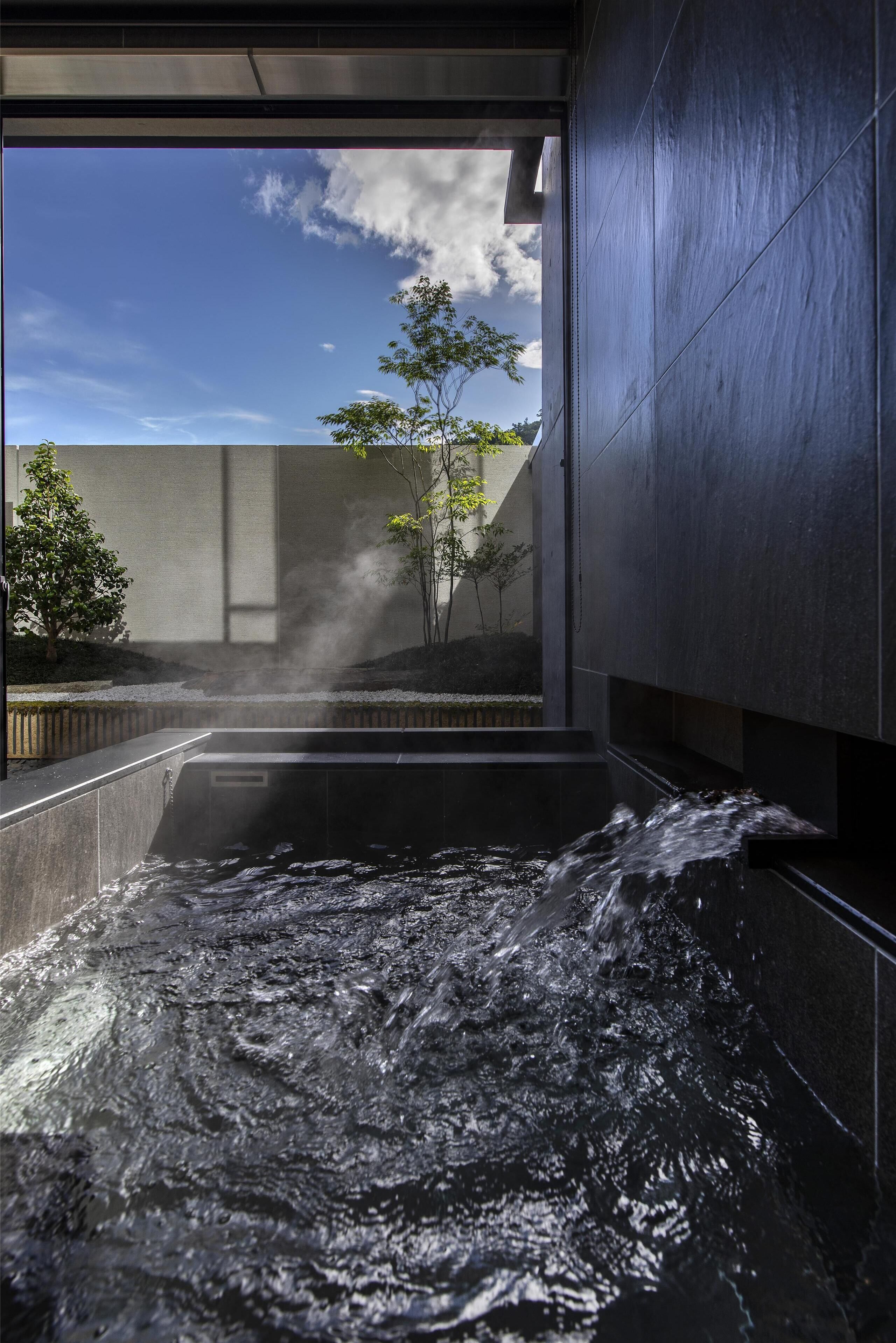 A spa area with a water feature, a view of the sky, and a tree.