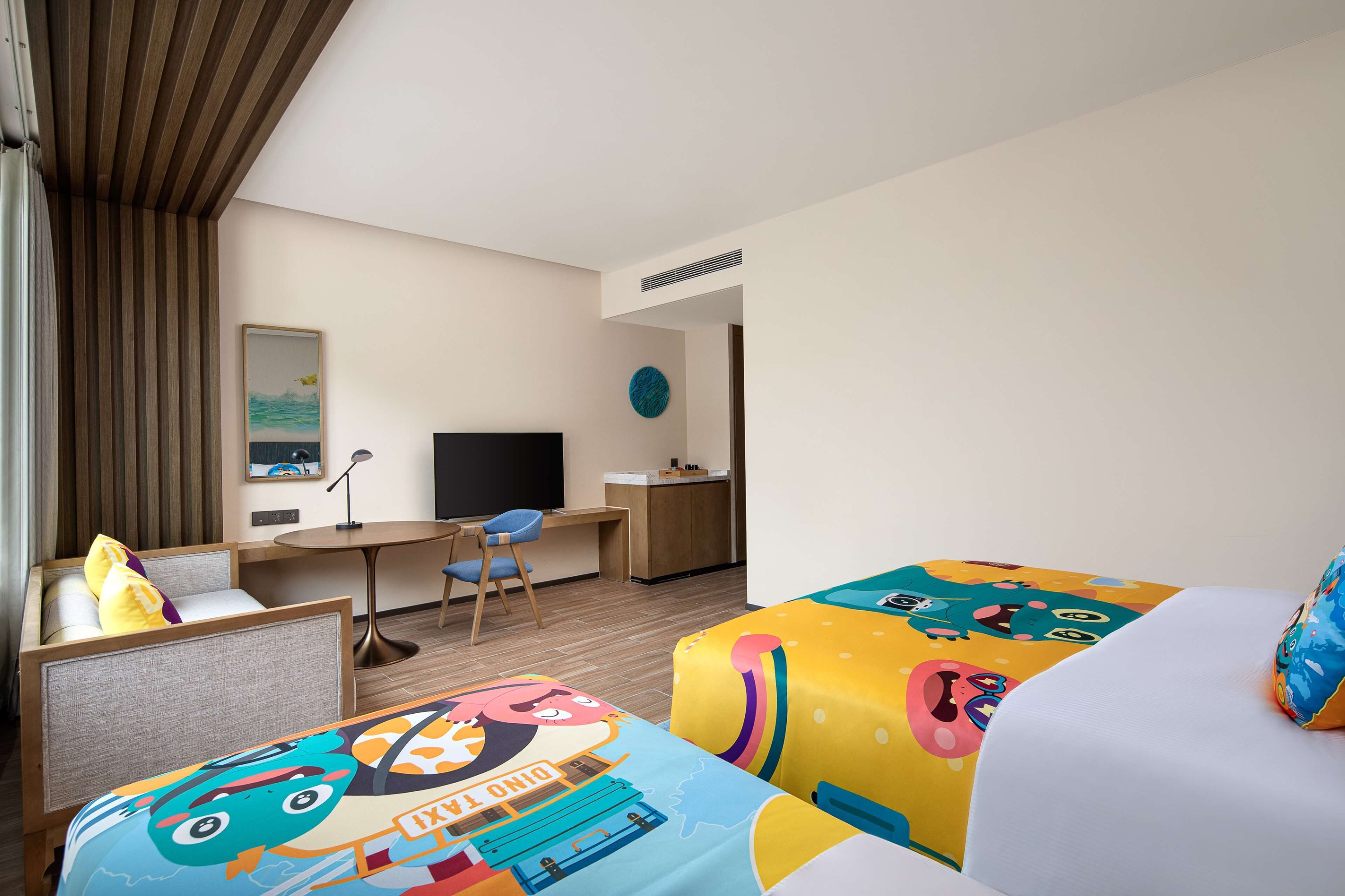 A hotel room with a bed, a desk, a chair, and a television.