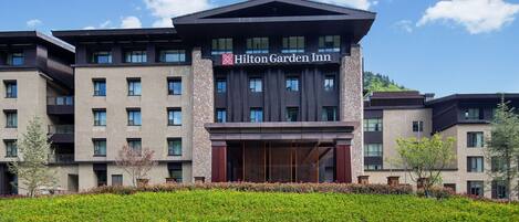 A Hilton Garden Inn hotel with a modern design, multiple floors, and a landscaped front garden.
