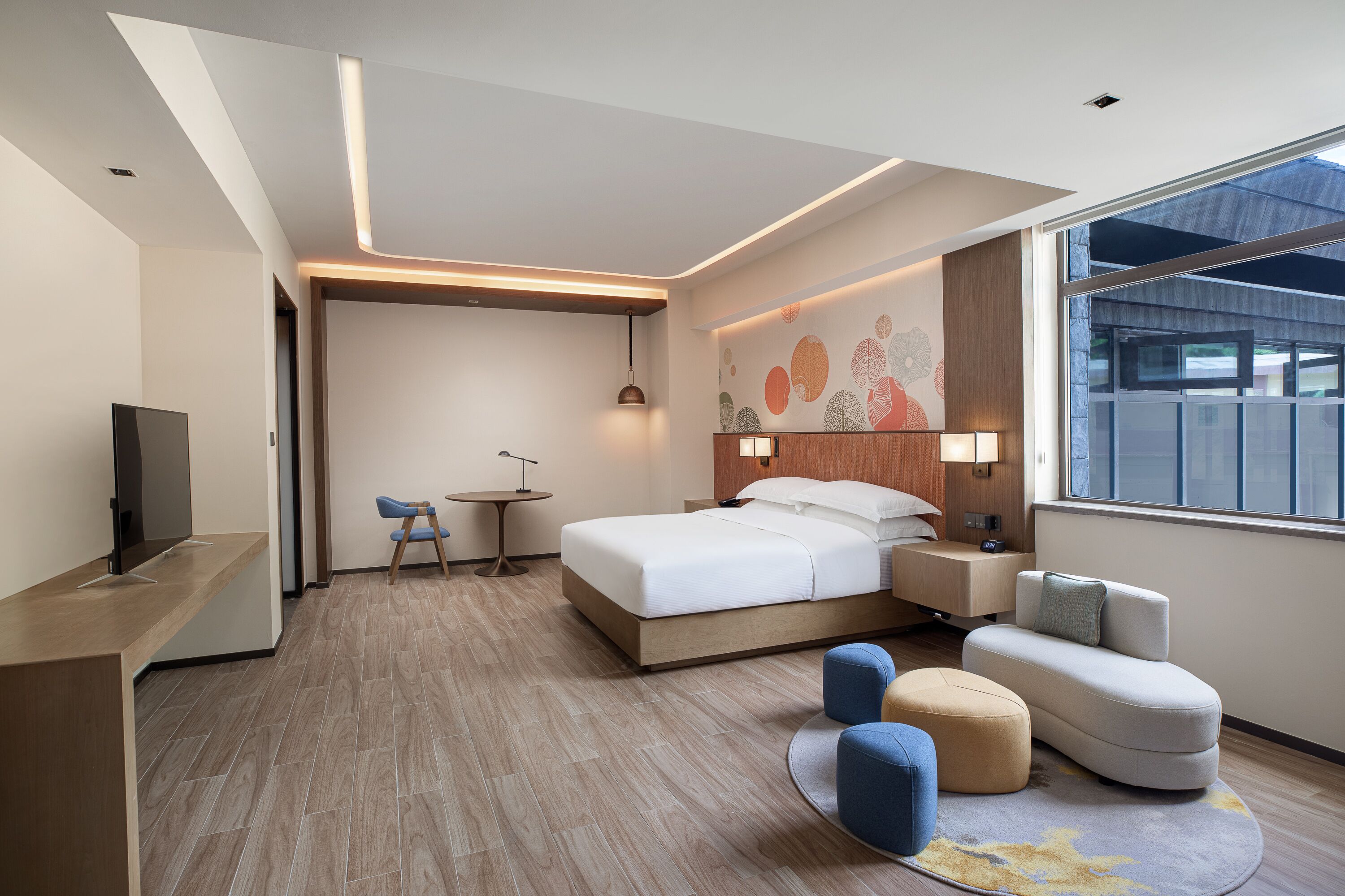 Una camera d'albergo moderna con un letto grande, una scrivania, una sedia, un tavolino e un divano.