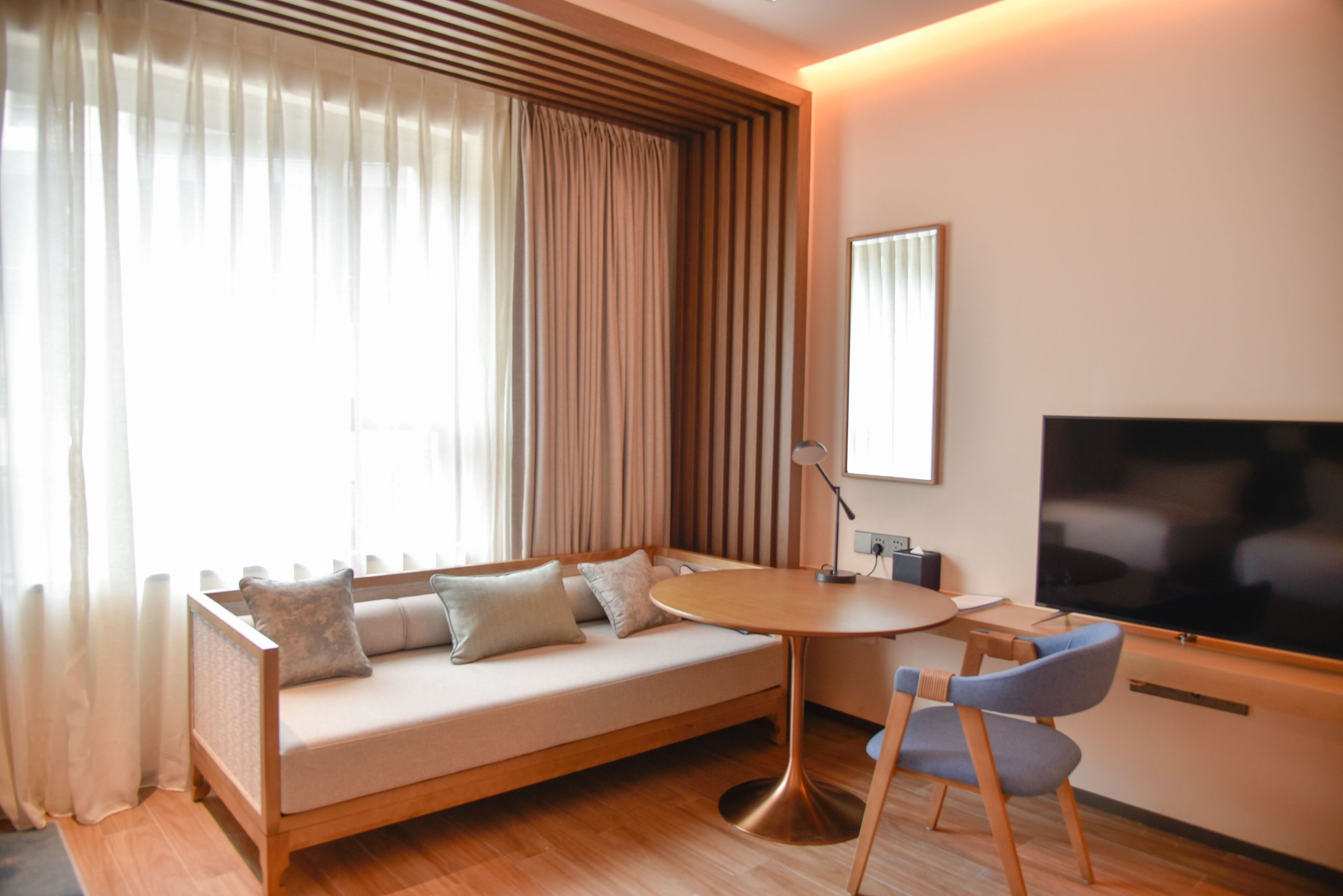 A modern living room with a sofa, a round table, and a TV.