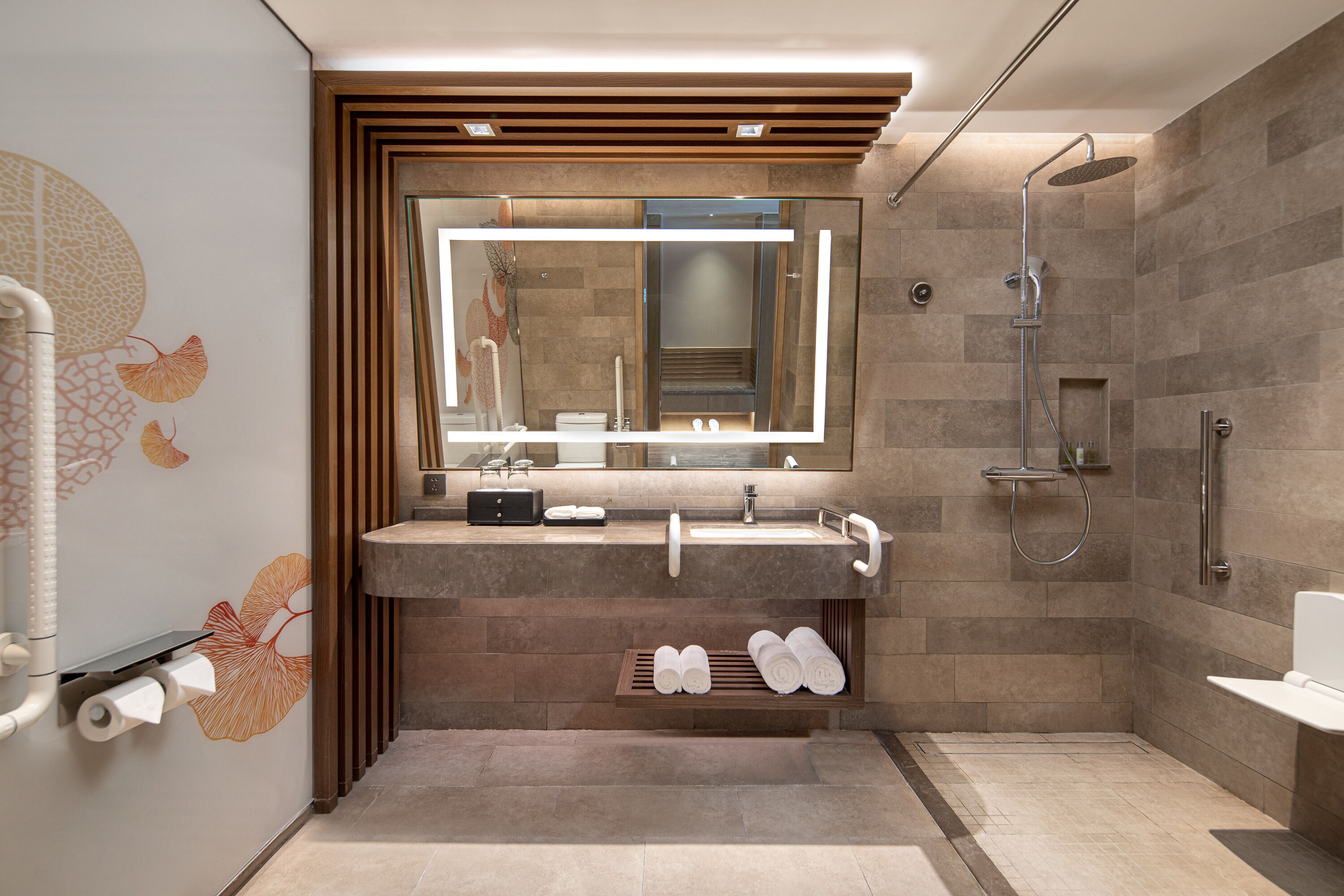Et moderne badeværelse med et toiletbord, et spejl, en bruser og et håndklædestativ.
