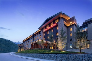 Un hotel moderno con fachada de piedra, varios pisos y una entrada destacada.