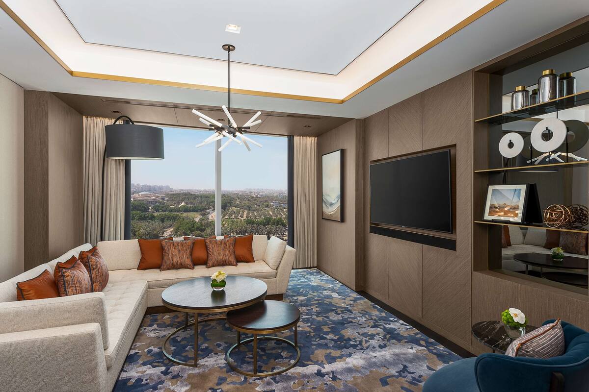Una sala de estar moderna con un sofá modular, una mesa de centro redonda y un televisor de pantalla plana grande.