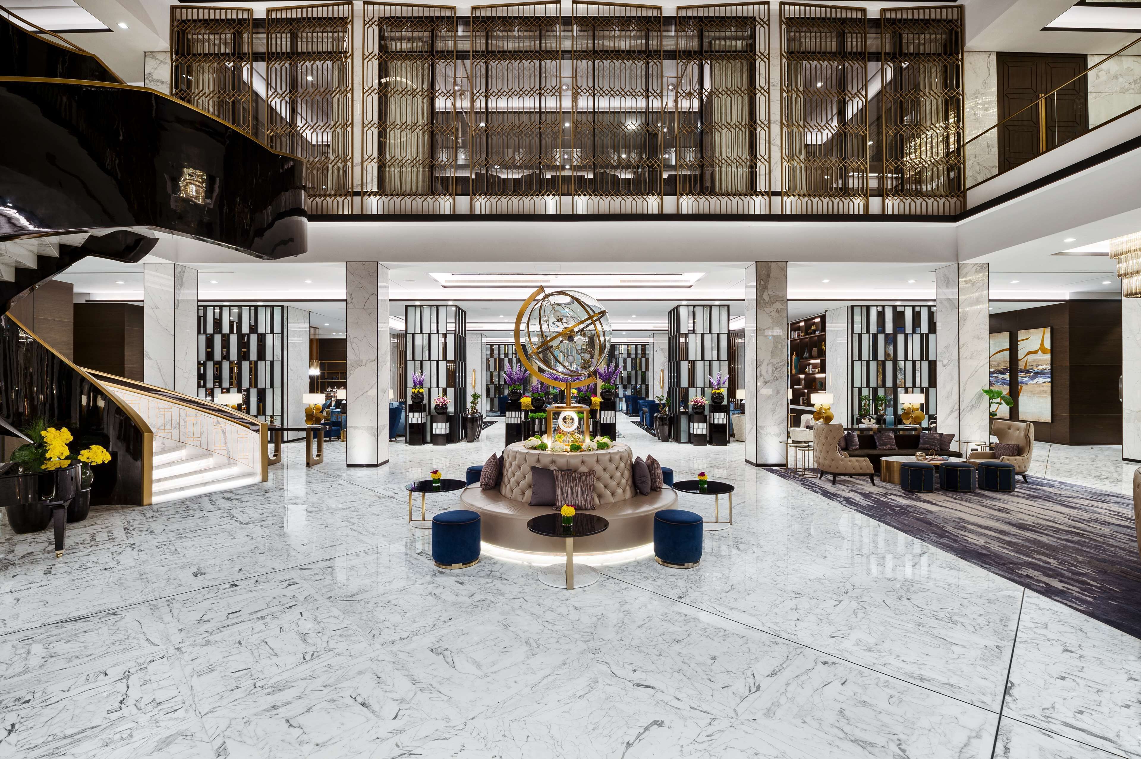 A spacious lobby with a central seating area, a staircase, and a decorative wall.