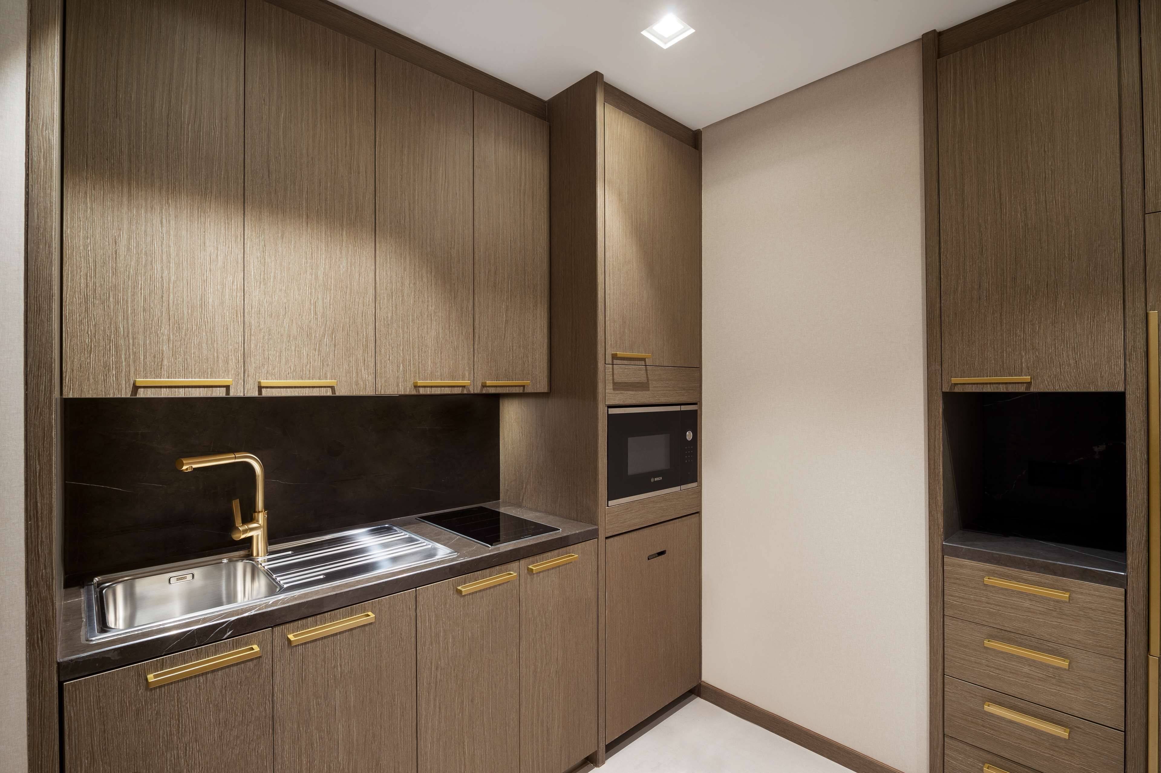 A modern kitchen with wooden cabinets, a stainless steel sink, and a built-in oven.