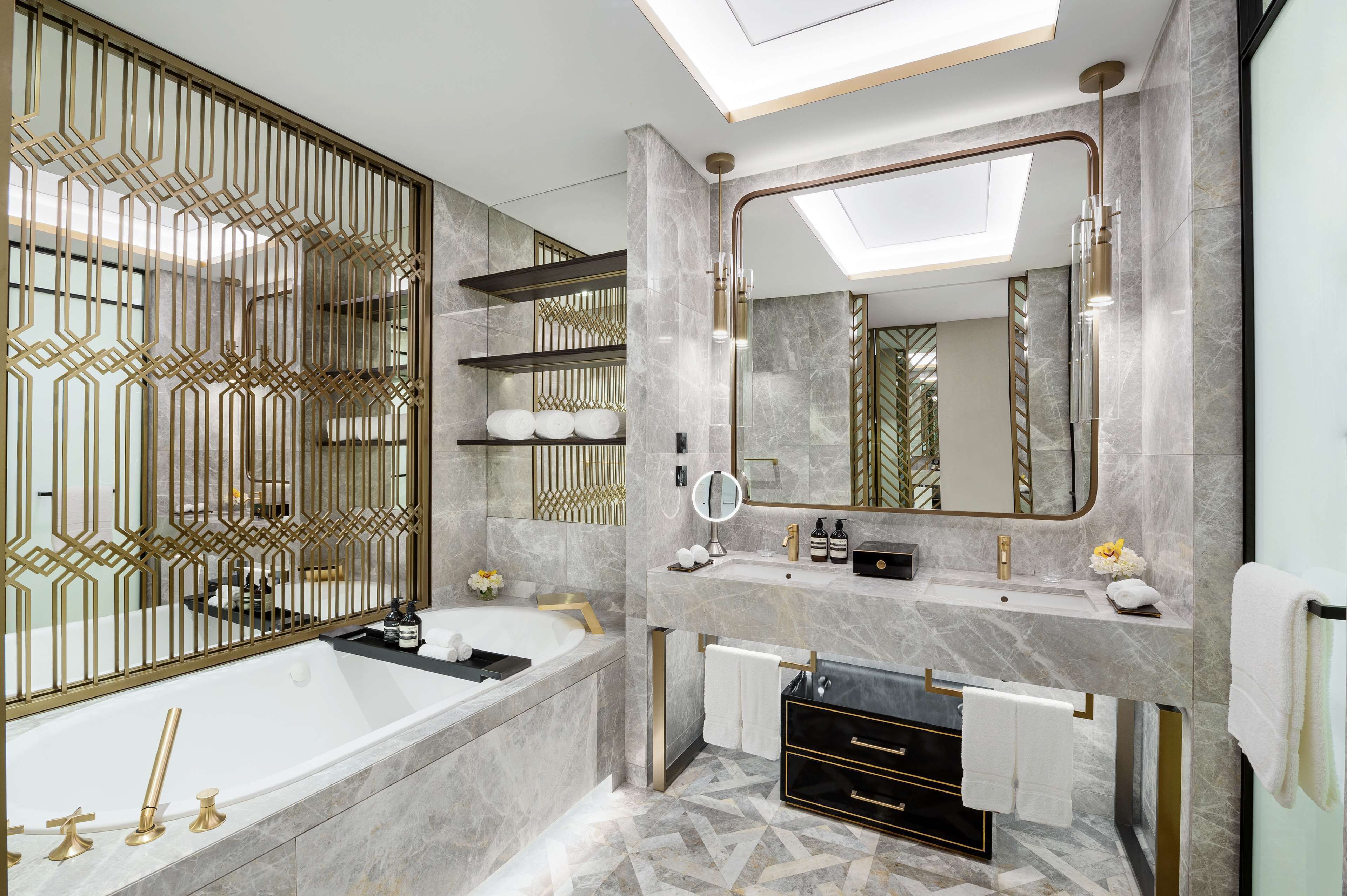 A modern bathroom with a large mirror, a bathtub, and a vanity with a sink and towel rack.
