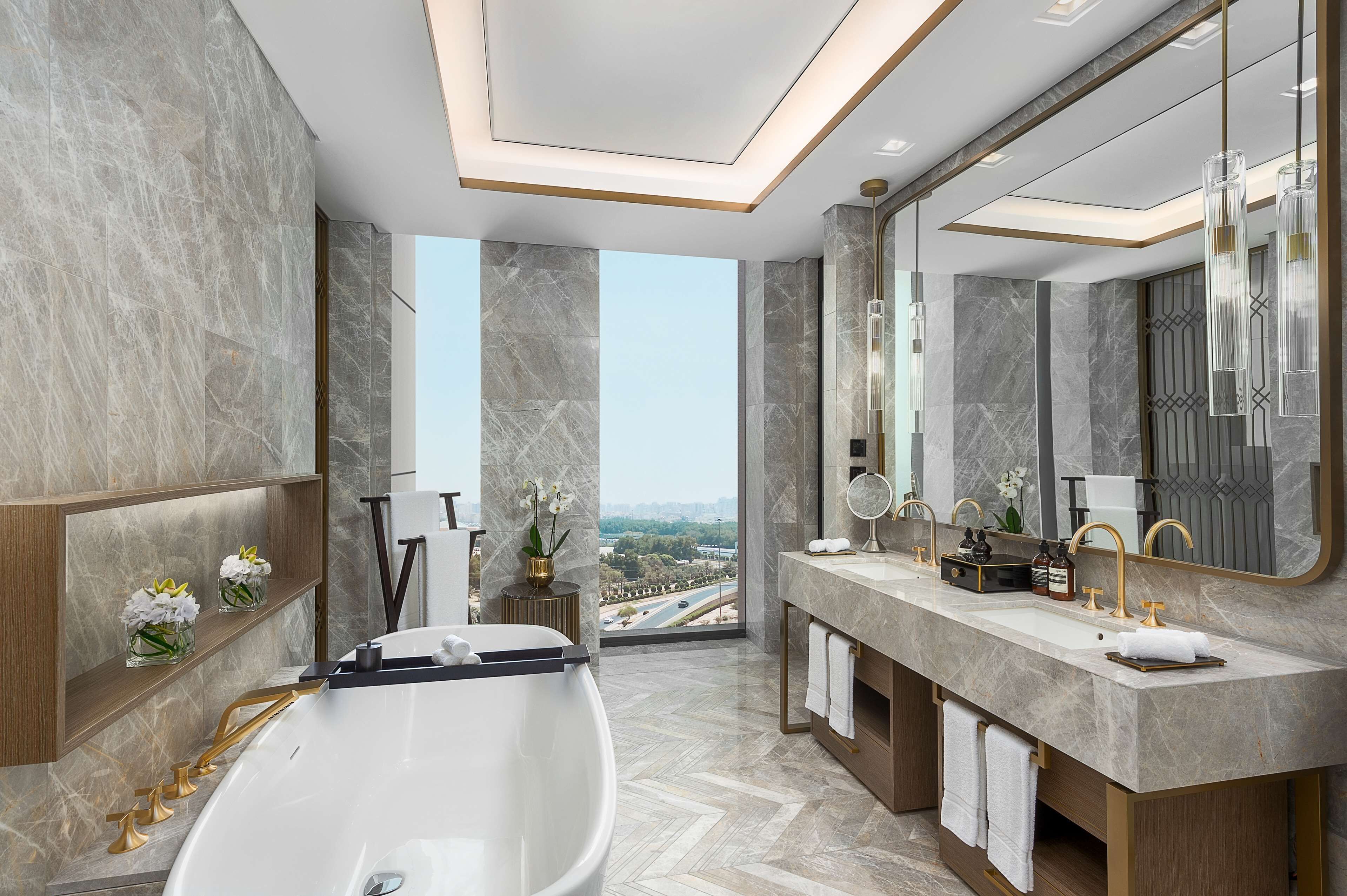 A modern bathroom with a large bathtub, dual sinks, and a large mirror.