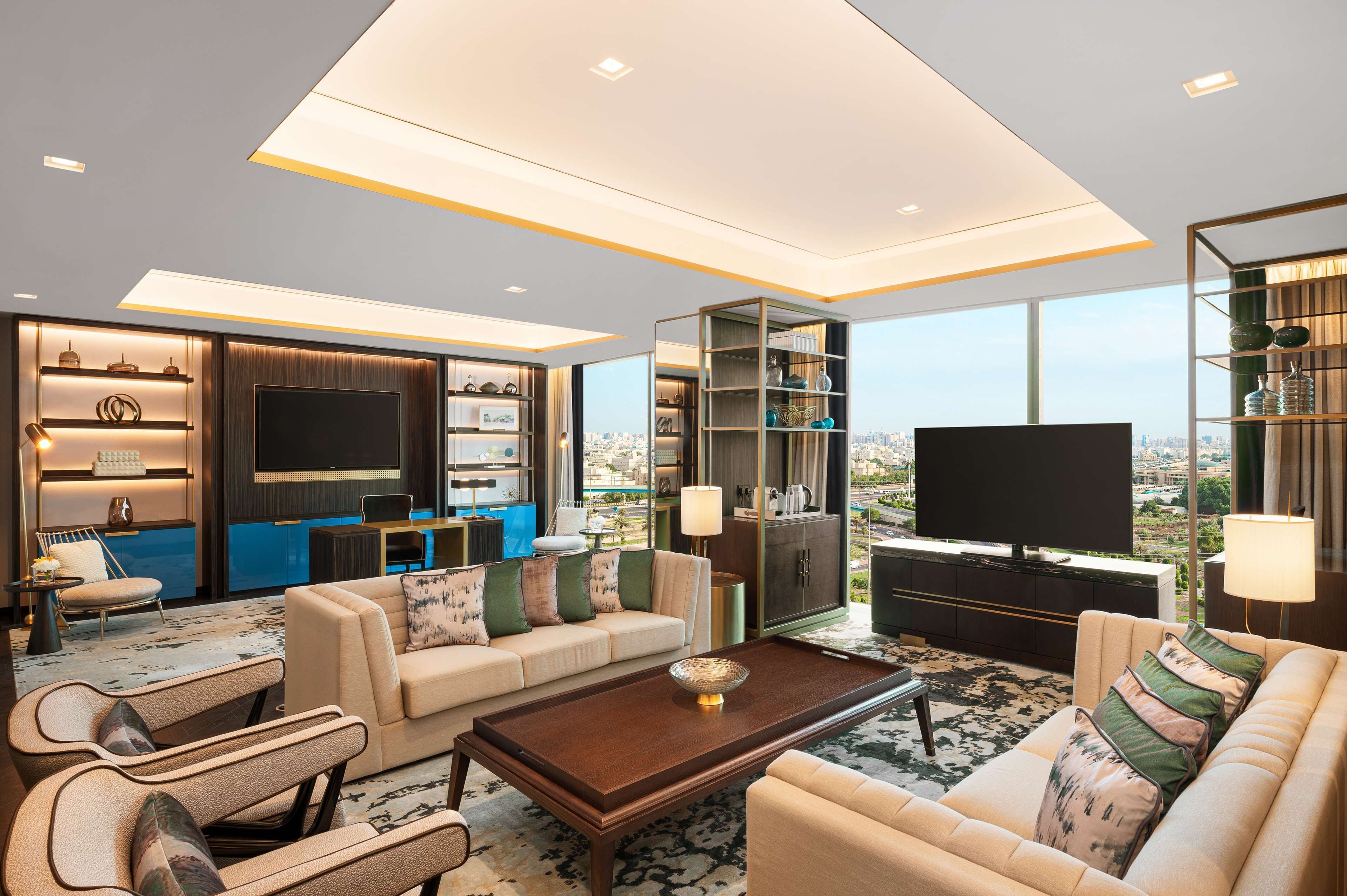 A modern living room with a large TV, comfortable seating, and a city view.