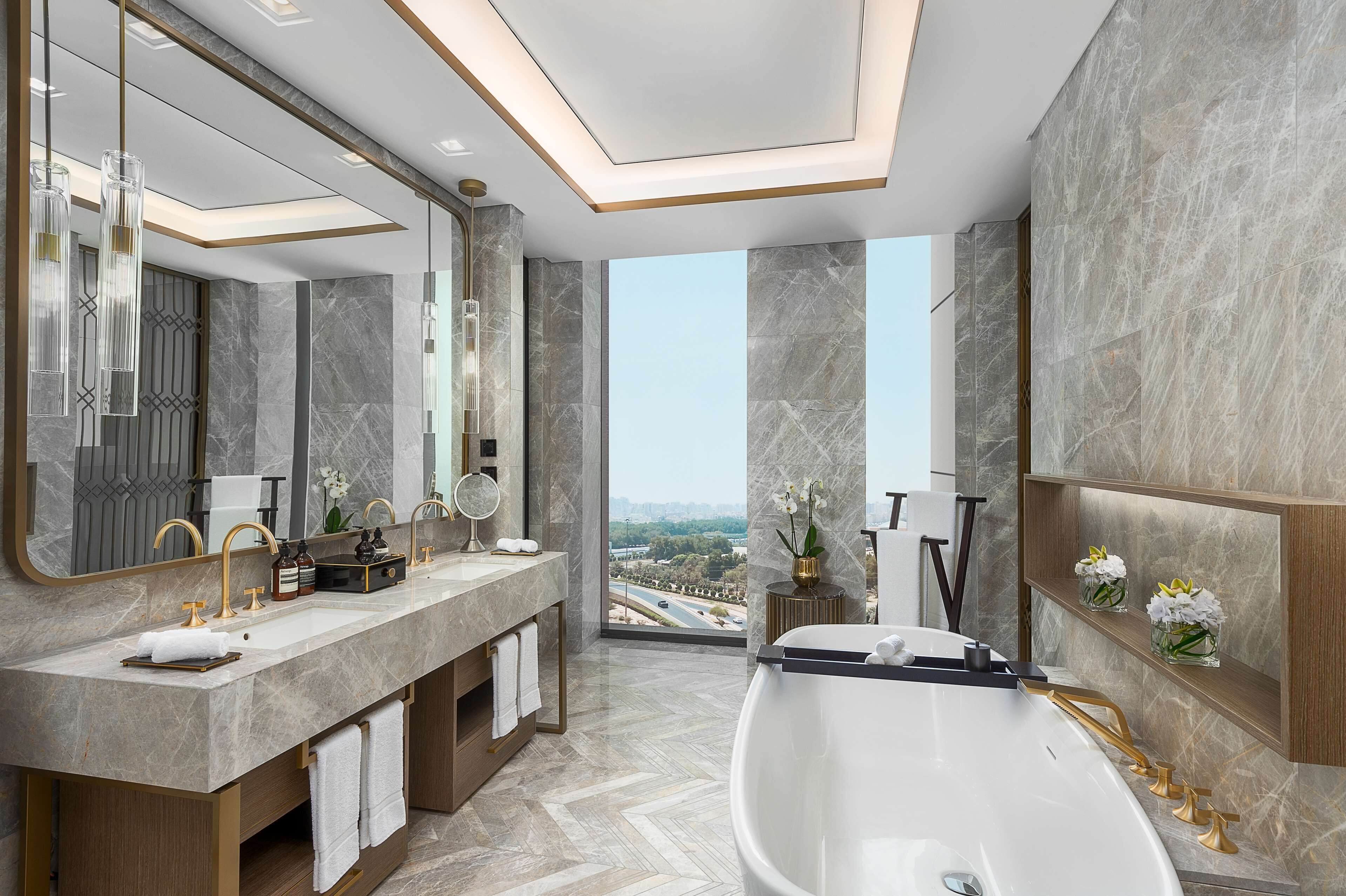 Une salle de bain moderne dotée d’une grande baignoire, de deux vasques et d’un grand miroir.