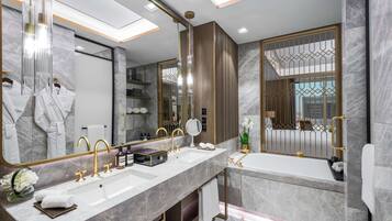 A modern bathroom with a large mirror, two sinks, a bathtub, and a vanity with a towel rack.