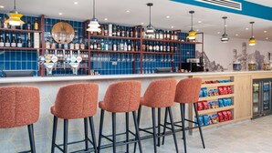 A bar area with stools, shelves of bottles, and a counter. - Hampton by Hilton Canterbury (Canterbury)