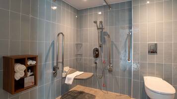 Un bagno moderno con doccia, servizi igienici e un armadietto in legno con asciugamani.