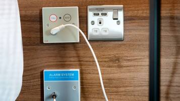 Un sistema de alarma instalado en la pared, un cargador USB y un enchufe.