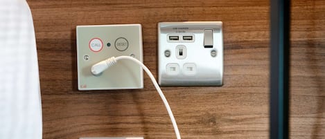 A wall-mounted alarm system, a USB charger, and a power outlet.