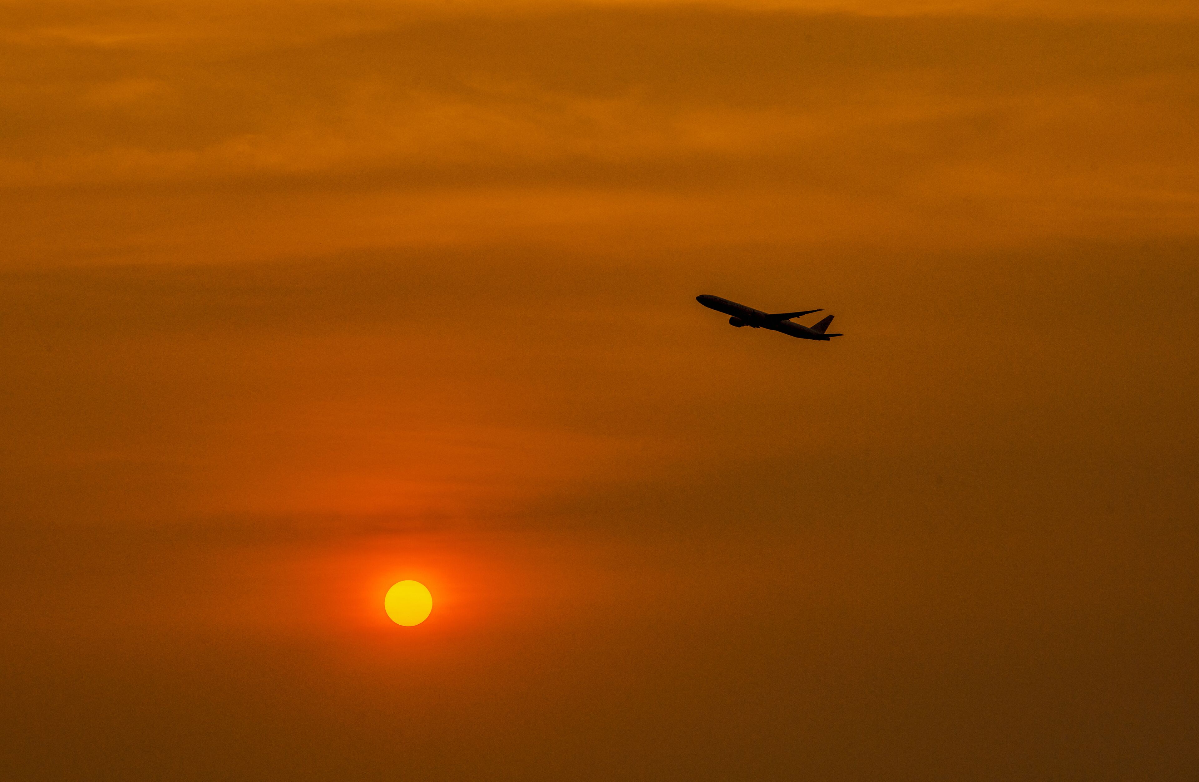 An airplane flying during sunset with a clear sky.