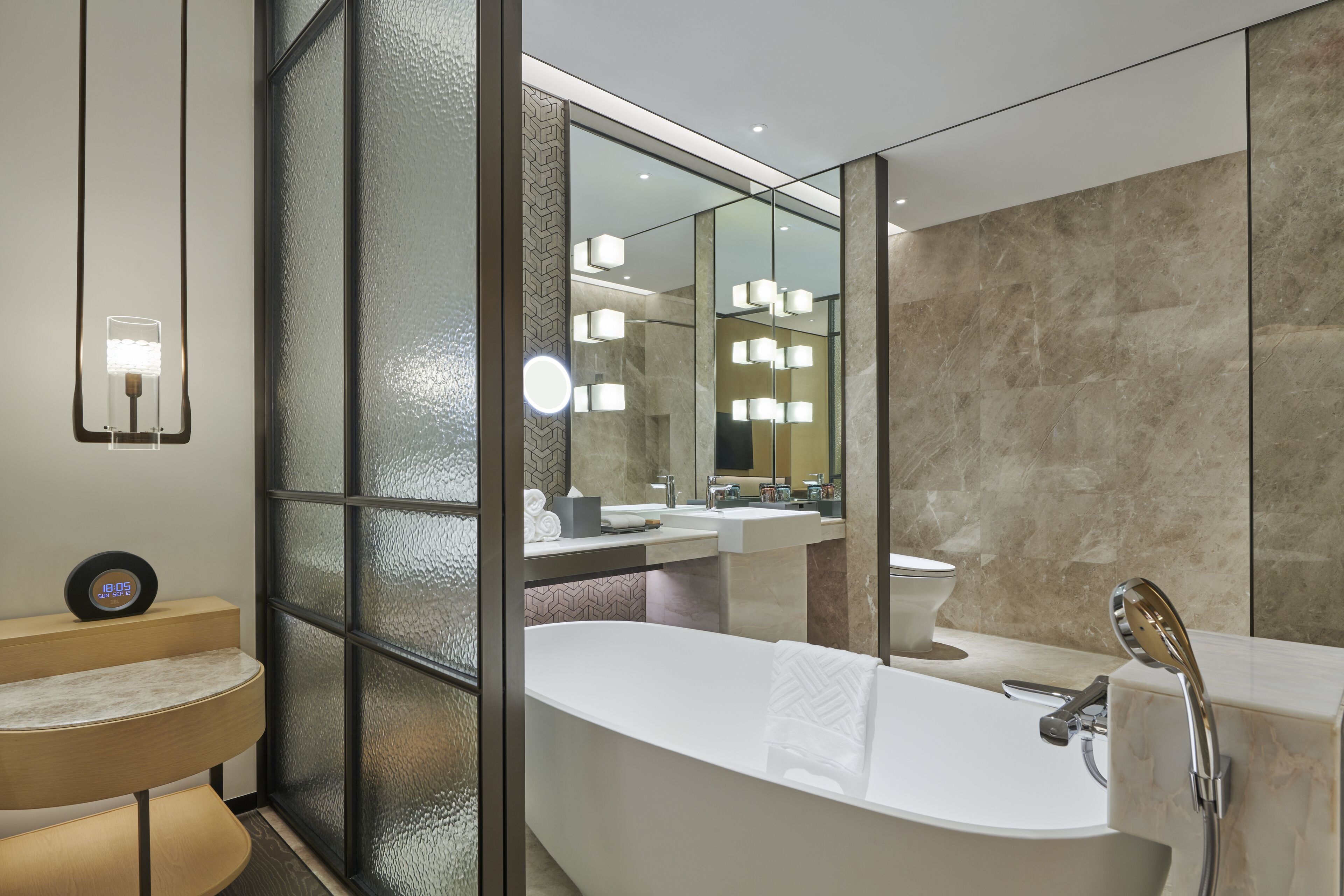 A modern bathroom with a freestanding bathtub, a vanity with a mirror, and a wall-mounted light fixture.