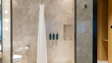 Une salle de bain moderne avec une douche à parois de verre, des murs en marbre et des toilettes.