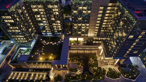 A high-rise building with multiple floors, large windows, and a central courtyard with pathways and greenery. - DoubleTree by Hilton Shenzhen Airport (Shenzhen)