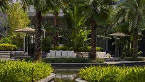 A serene outdoor area with a pool, palm trees, and a seating area with a sofa and chairs. - DoubleTree by Hilton Shenzhen Airport (Shenzhen)