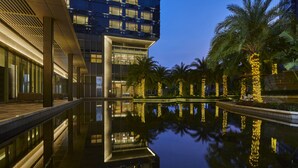 A modern building with a reflective pool and palm trees. - DoubleTree by Hilton Shenzhen Airport (Shenzhen)