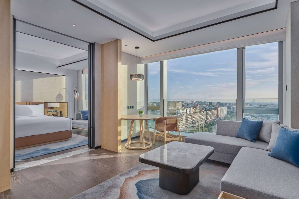 Ett modernt hotellrum med en stor säng, en soffa, en matplats och utsikt över staden.