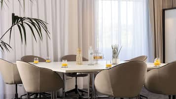A conference room with a round table, six chairs, and a large window with curtains.