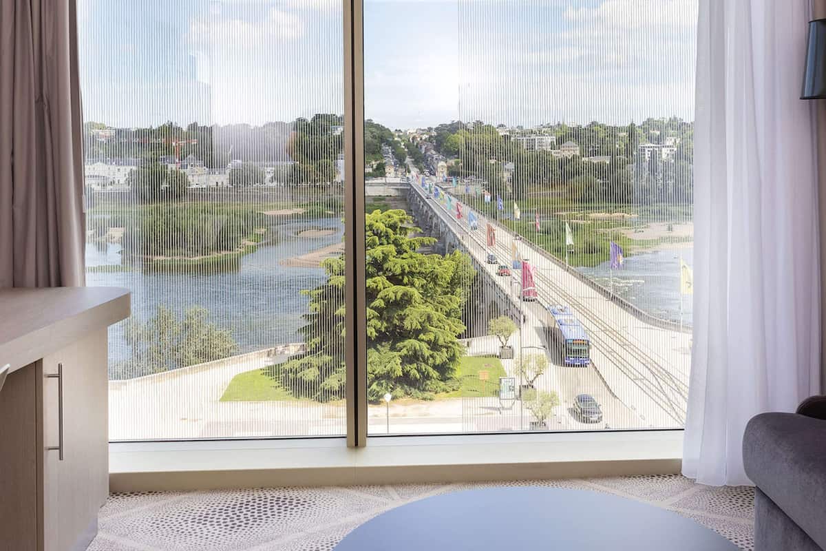 A room with a large window overlooking a river and a bridge.