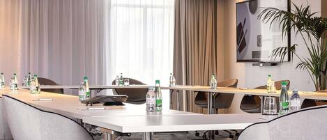 A conference room with a long table, chairs, and a projector screen.