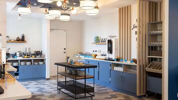 Een moderne keuken met blauwe kastjes, een centraal eiland en diverse apparaten.