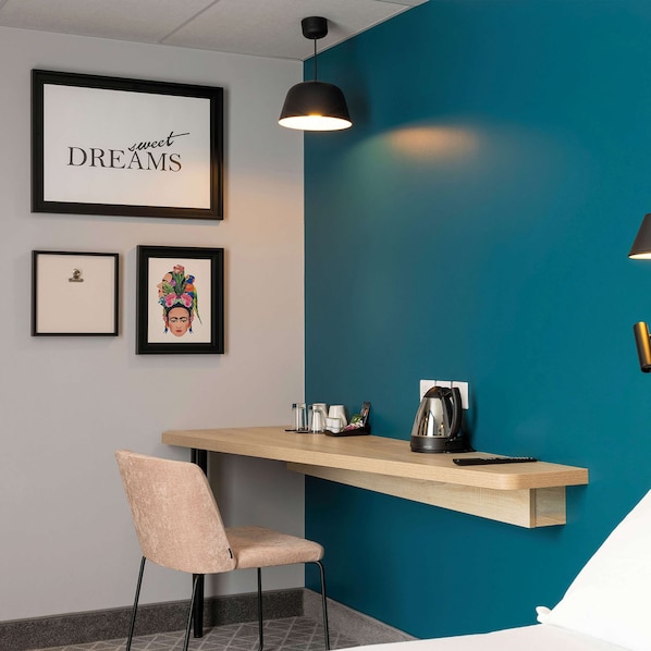 A modern room with a teal accent wall, a framed inspirational quote, a coffee maker, and a chair. - Hampton by Hilton Tours Centre (Tours)