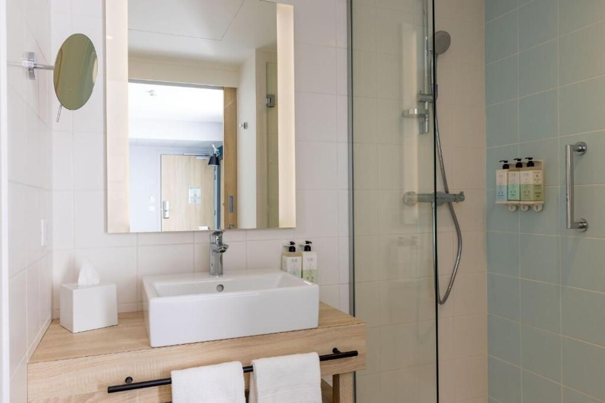 Un baño moderno con un lavamanos blanco, un espejo y una ducha.