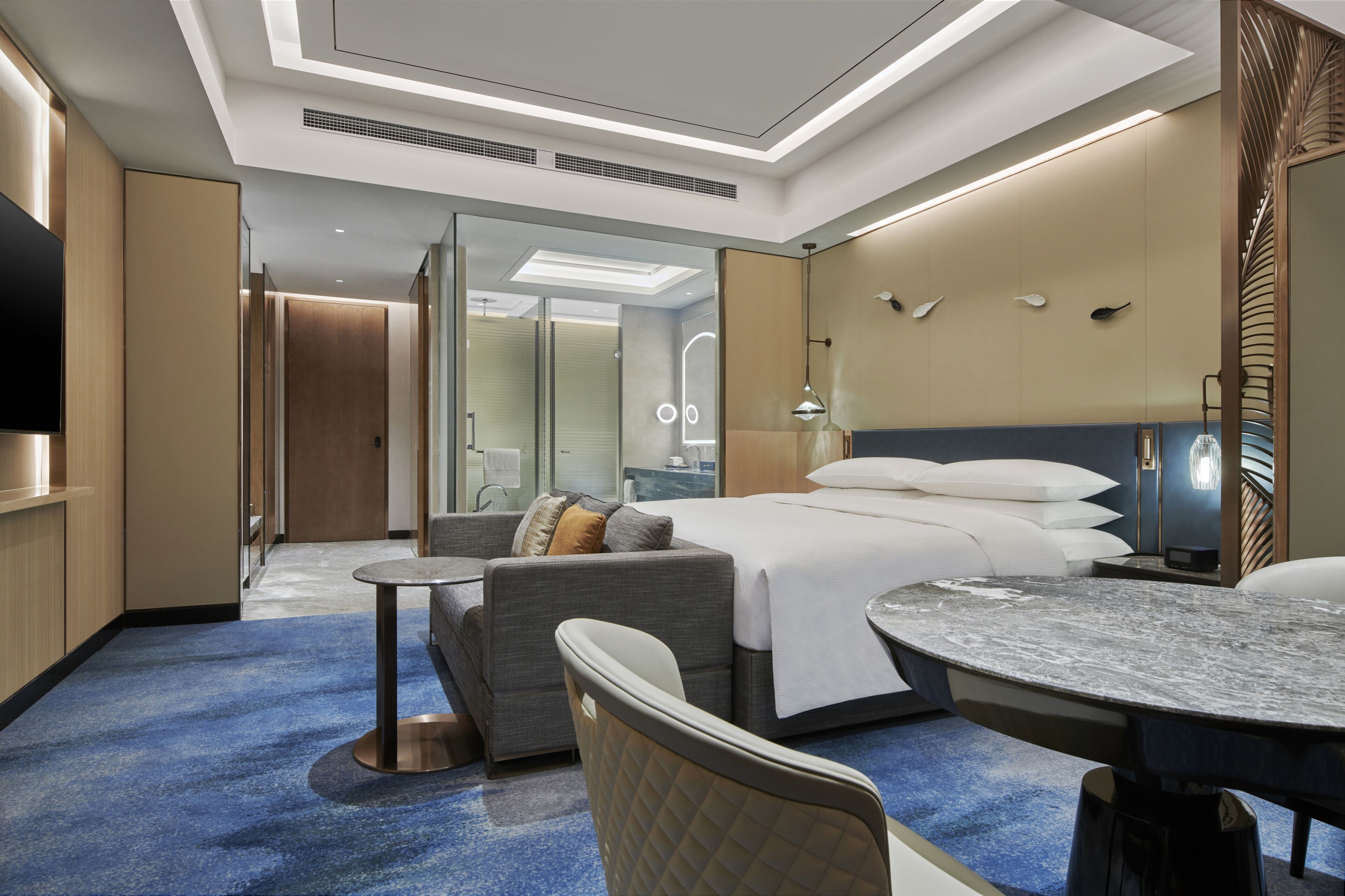 Una habitación de hotel moderna con cama, sofá y mesa redonda.