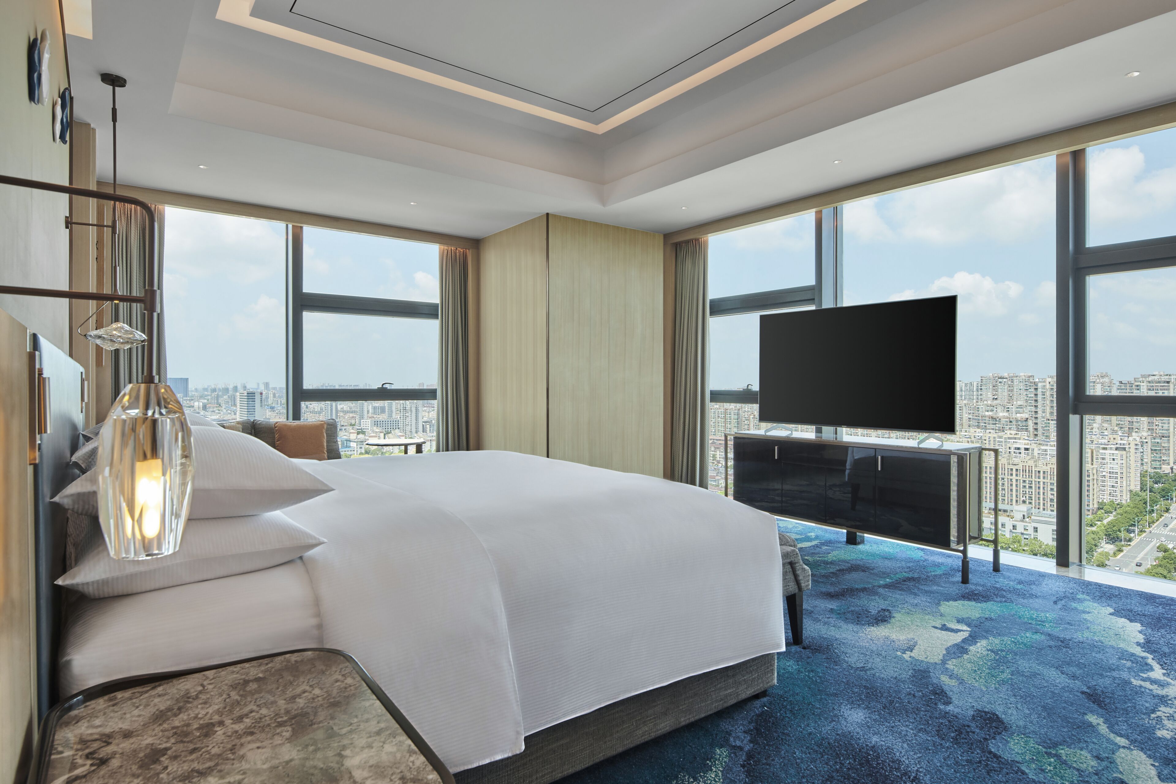 Una habitación de hotel moderna con una cama grande, un televisor de pantalla plana y vistas a la ciudad.