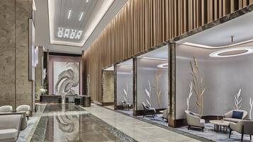 A modern lobby with a reception desk, seating area, and decorative wall panels.