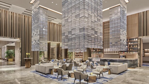 A spacious lobby with high ceilings, a central seating area, and a bar. - Hilton Yancheng (Yancheng)